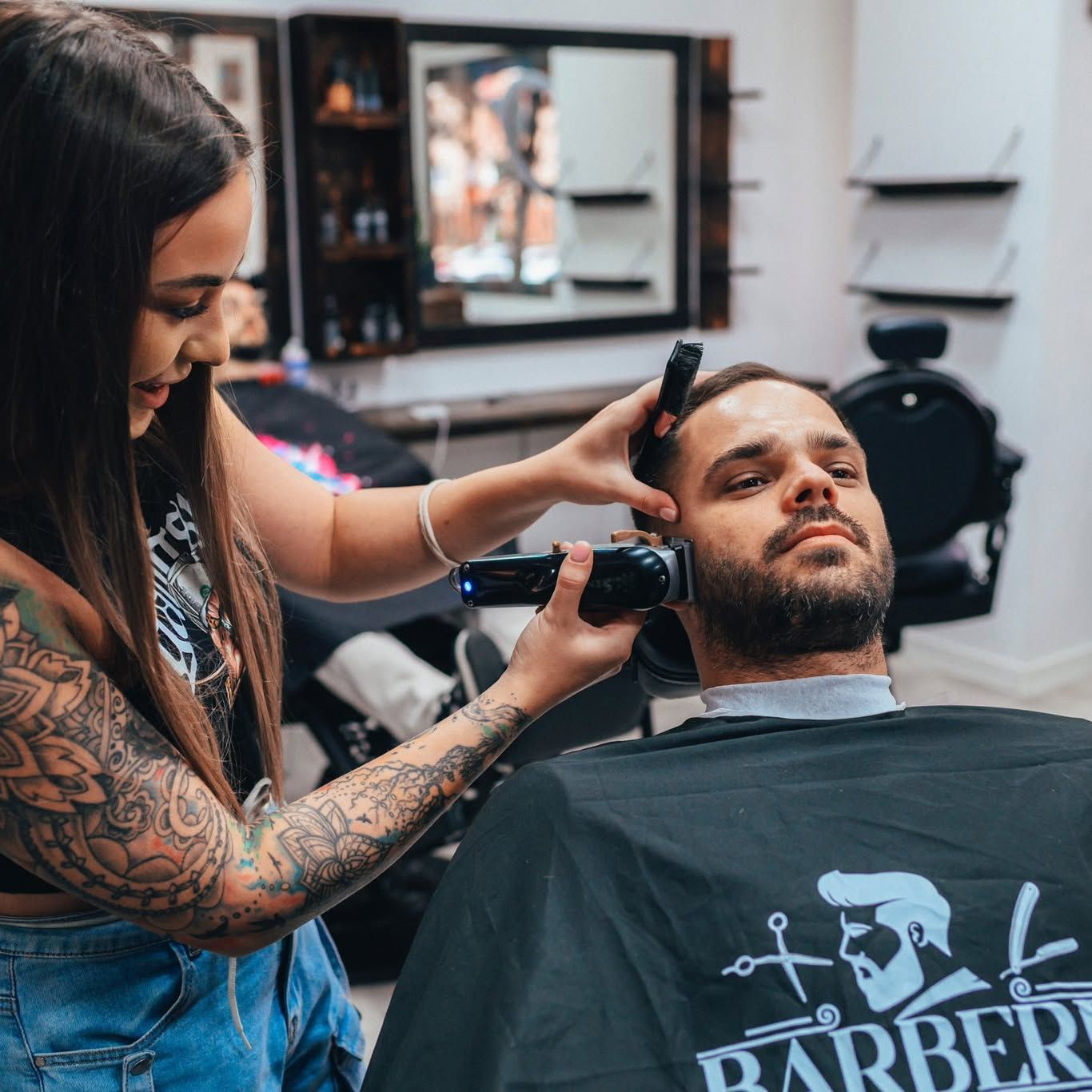 Anett pri práci so strojčekom, v pozadí interiér barbershopu